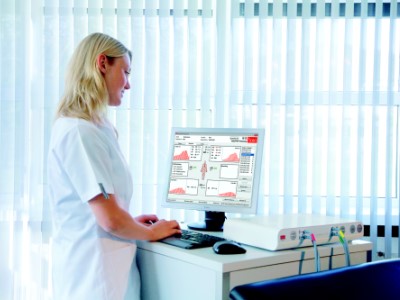 Eine Ärztin steht vor einem Monitor, der Messergebnisse anzeigt